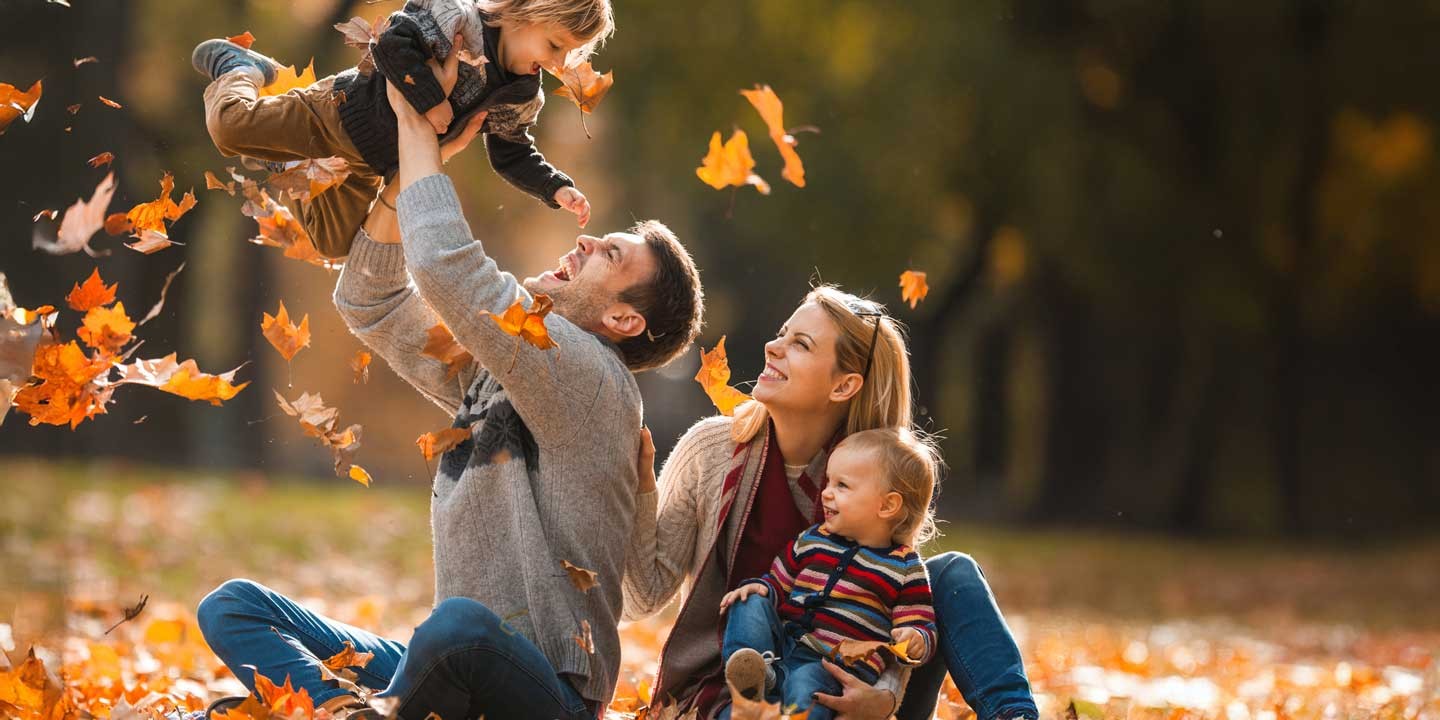 Family playing in fall leaves