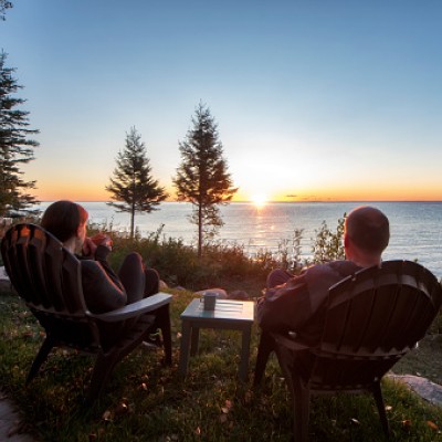 two people sitting by a lake at sunset