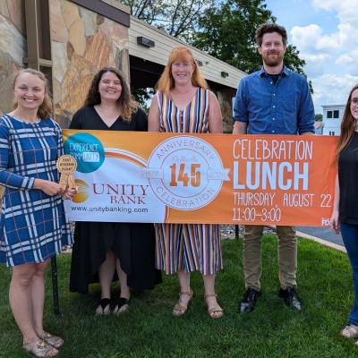 people holding an anniversary celebration lunch banner
